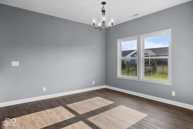 empty room featuring baseboards, visible vents, a chandelier, and dark wood-style flooring