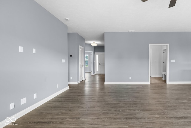 unfurnished living room featuring ceiling fan, dark wood finished floors, and baseboards