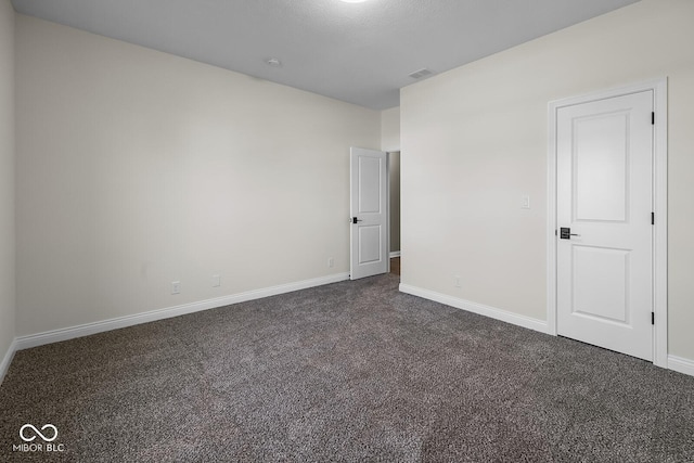 unfurnished room with dark carpet and baseboards