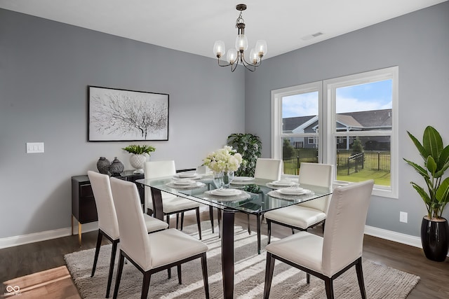 dining area with a chandelier, wood finished floors, visible vents, and baseboards