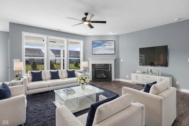 living room featuring dark wood-style floors, a glass covered fireplace, and baseboards