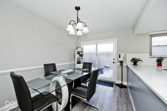 dining area with dark hardwood / wood-style flooring, a wealth of natural light, an inviting chandelier, and a textured ceiling