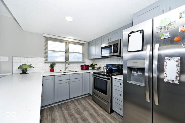 kitchen with a textured ceiling, stainless steel appliances, dark hardwood / wood-style floors, and sink