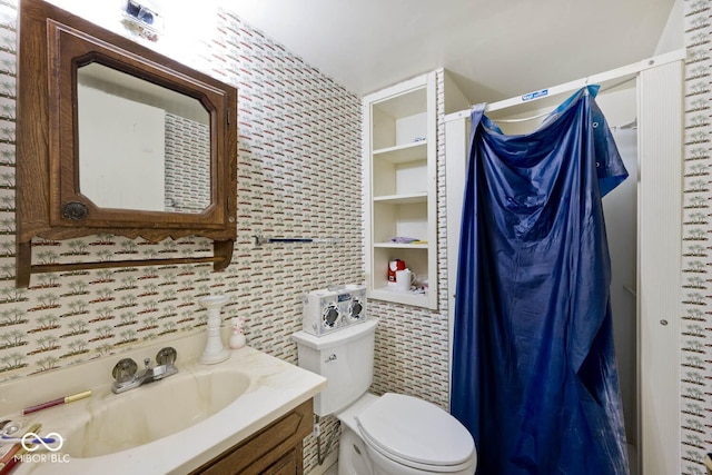 bathroom featuring toilet, vanity, and built in shelves