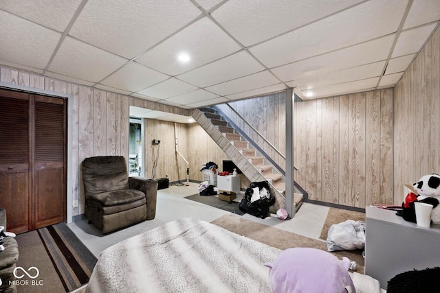 bedroom featuring a closet, a drop ceiling, and wooden walls