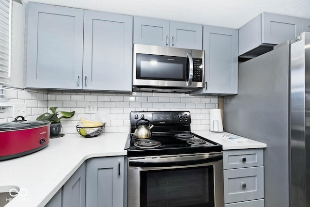 kitchen featuring a textured ceiling, appliances with stainless steel finishes, and tasteful backsplash