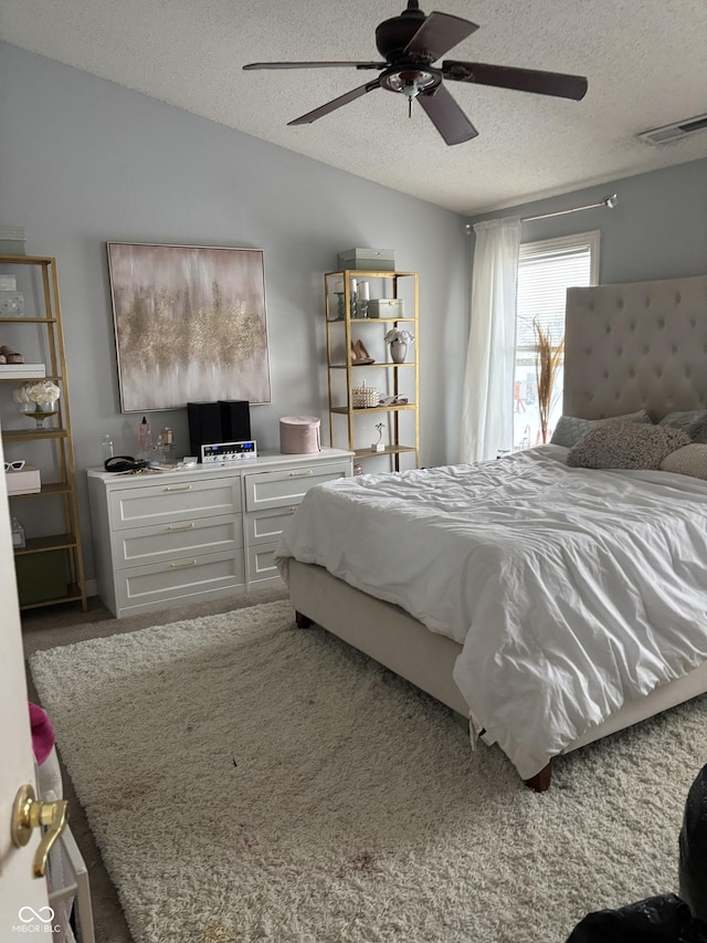 carpeted bedroom featuring ceiling fan and a textured ceiling