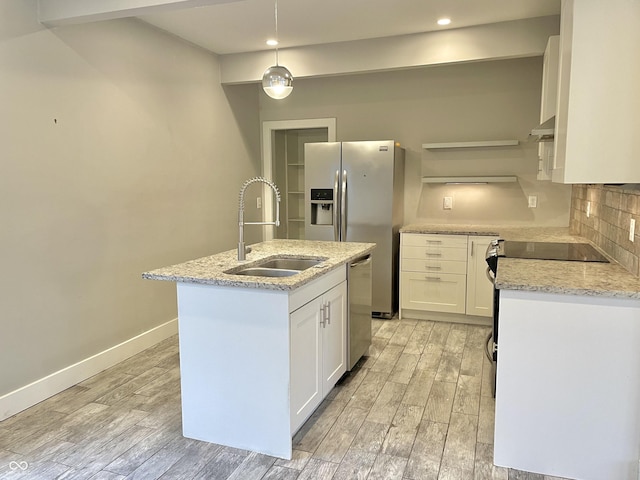 kitchen with appliances with stainless steel finishes, sink, white cabinetry, and a center island with sink