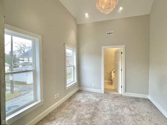 carpeted empty room with high vaulted ceiling