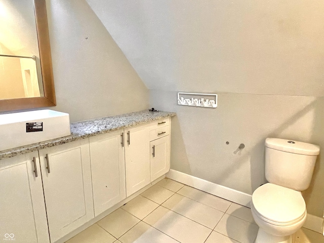 bathroom with vaulted ceiling, toilet, tile patterned floors, and vanity