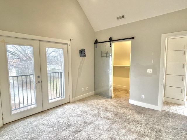 doorway to outside with lofted ceiling, a barn door, french doors, and light colored carpet