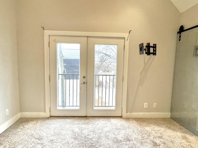 doorway with light carpet, a barn door, vaulted ceiling, and french doors