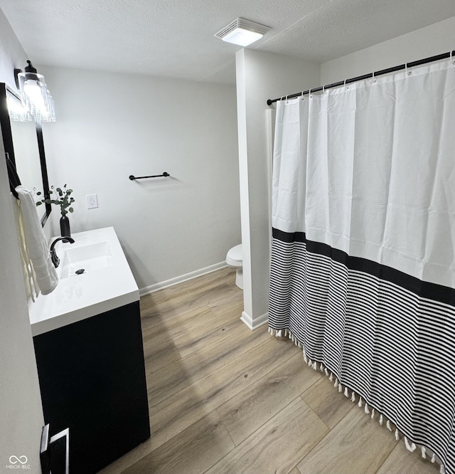 bathroom featuring vanity, toilet, wood-type flooring, and a textured ceiling