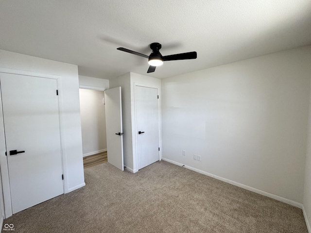 unfurnished bedroom with ceiling fan, light carpet, and a textured ceiling