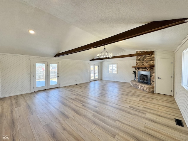 unfurnished living room featuring vaulted ceiling with beams, a chandelier, light hardwood / wood-style floors, a brick fireplace, and a textured ceiling