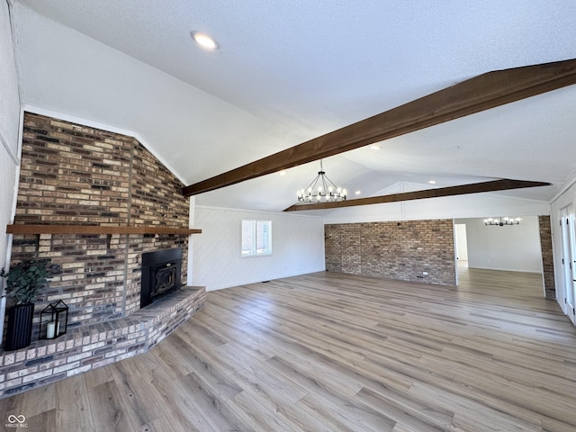 unfurnished living room featuring a notable chandelier, light hardwood / wood-style flooring, lofted ceiling with beams, and brick wall