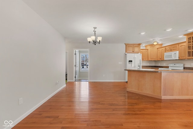 kitchen featuring kitchen peninsula, white appliances, light brown cabinets, a chandelier, and light hardwood / wood-style floors