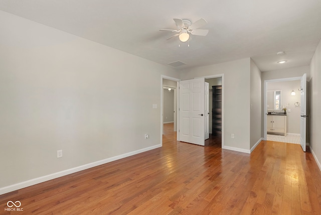 unfurnished bedroom featuring hardwood / wood-style floors, ceiling fan, a walk in closet, and a closet