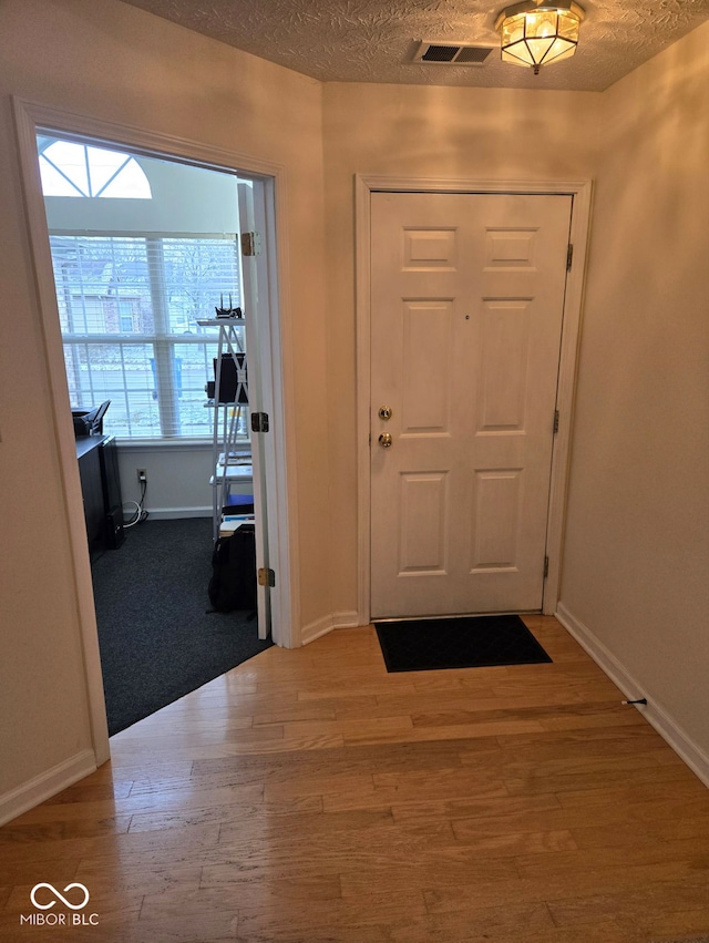 entrance foyer with wood-type flooring, a textured ceiling, and a wealth of natural light