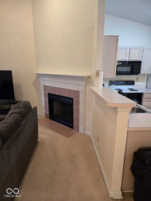 living room with sink, light colored carpet, vaulted ceiling, and a tiled fireplace