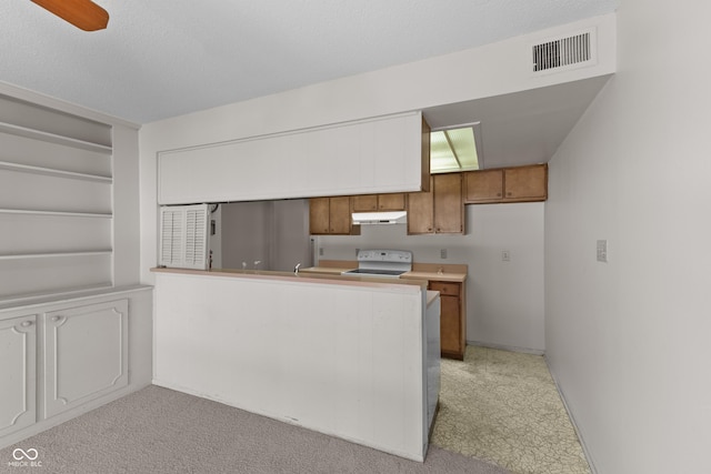 kitchen with electric stove, light colored carpet, and kitchen peninsula