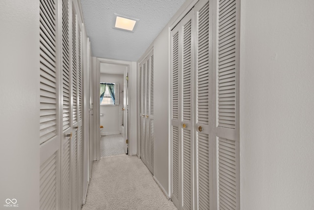 hallway featuring light carpet and a textured ceiling