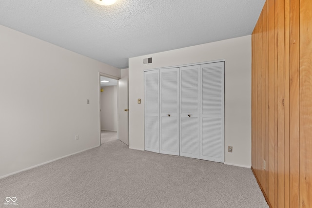 unfurnished bedroom with light carpet, a textured ceiling, and a closet