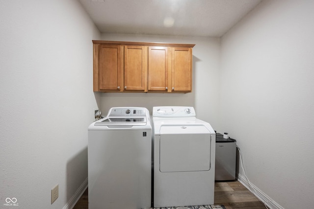 clothes washing area featuring cabinet space, dark wood-style floors, baseboards, and separate washer and dryer