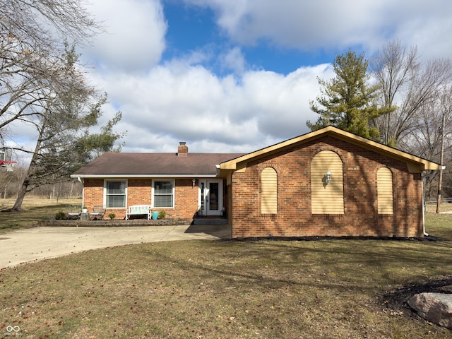 view of front facade featuring a front lawn, a chimney, and brick siding