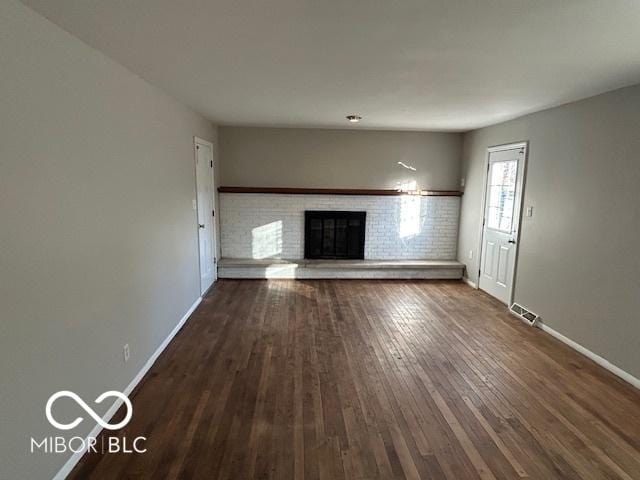 unfurnished living room with a fireplace and dark wood-type flooring