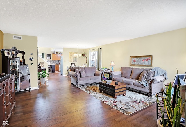 living room with a textured ceiling, dark hardwood / wood-style flooring, and a notable chandelier