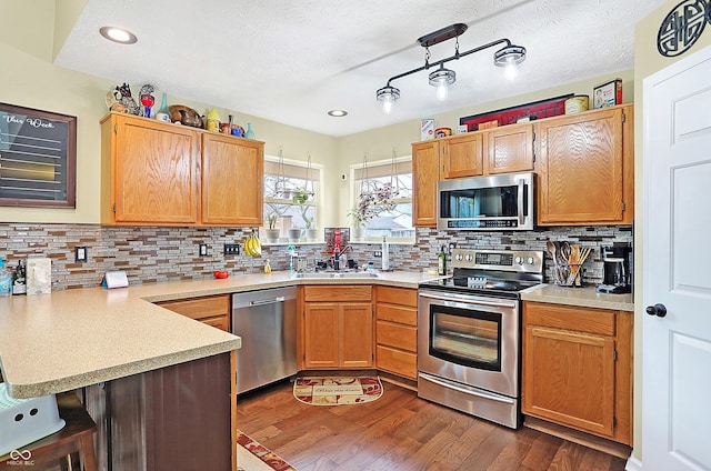 kitchen with stainless steel appliances, dark hardwood / wood-style floors, kitchen peninsula, a kitchen bar, and decorative backsplash