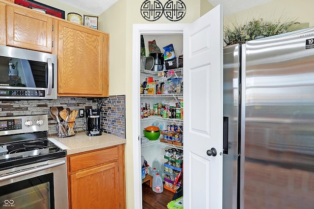 kitchen with decorative backsplash, stainless steel appliances, a textured ceiling, and wood-type flooring