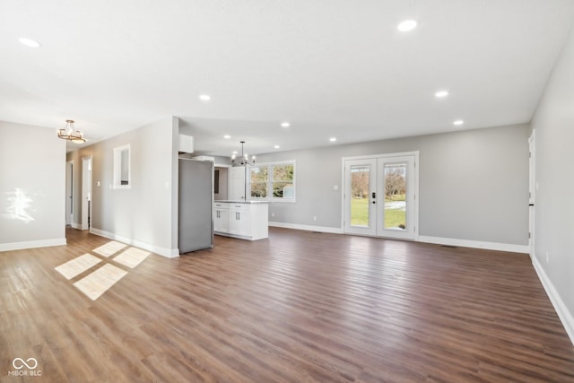 unfurnished living room featuring a notable chandelier, wood-type flooring, and french doors