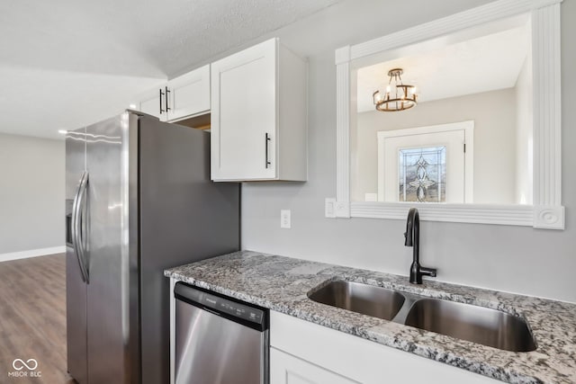 kitchen featuring sink, white cabinetry, appliances with stainless steel finishes, dark hardwood / wood-style flooring, and light stone countertops