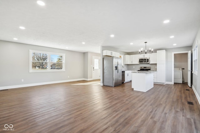 kitchen featuring appliances with stainless steel finishes, pendant lighting, washer / clothes dryer, white cabinets, and a center island