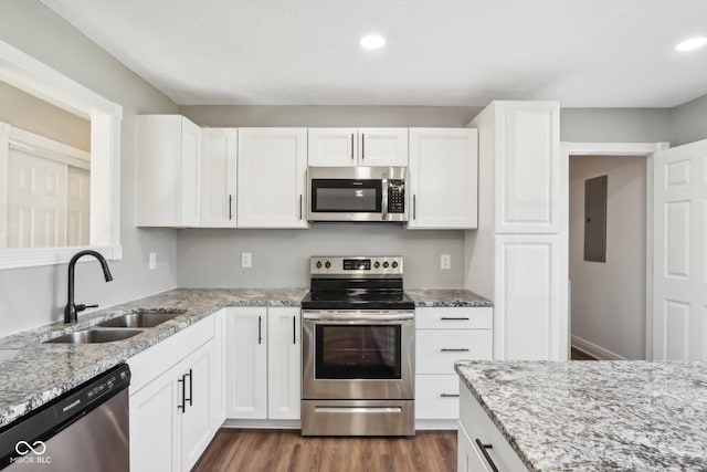 kitchen featuring appliances with stainless steel finishes, dark hardwood / wood-style floors, sink, white cabinets, and light stone counters