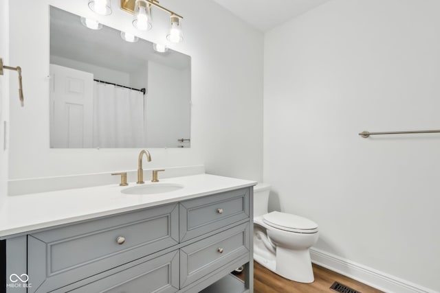 bathroom featuring vanity, wood-type flooring, and toilet