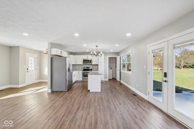 kitchen featuring pendant lighting, white cabinetry, a center island, a notable chandelier, and stainless steel appliances