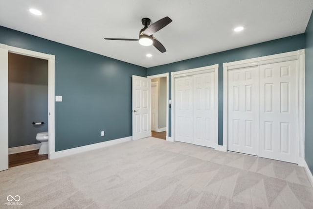 unfurnished bedroom featuring multiple closets, ceiling fan, connected bathroom, and light carpet