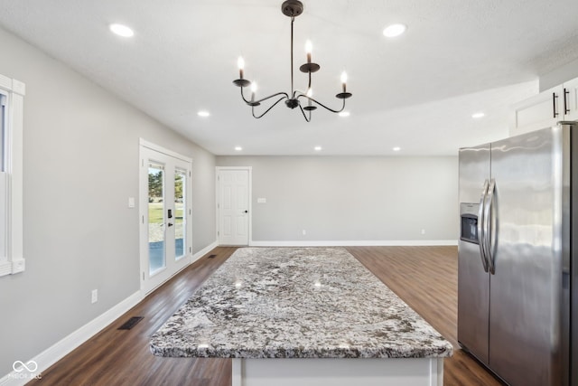 kitchen featuring decorative light fixtures, white cabinetry, stainless steel fridge, light stone countertops, and french doors