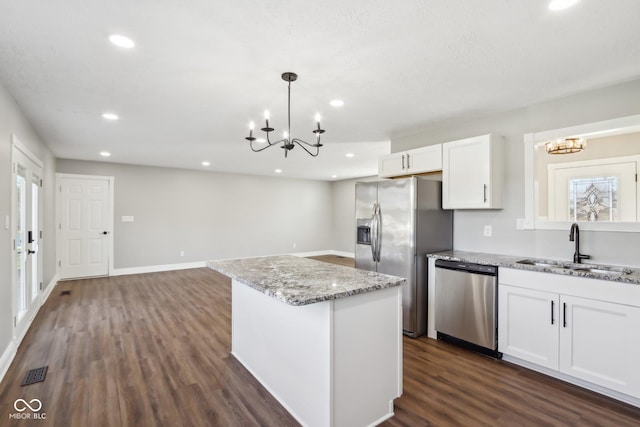 kitchen with sink, hanging light fixtures, stainless steel appliances, light stone countertops, and white cabinets