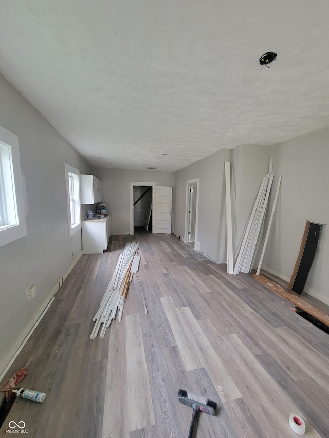 unfurnished living room featuring lofted ceiling, a textured ceiling, and light hardwood / wood-style flooring