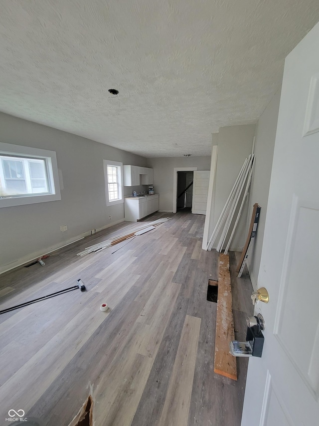 unfurnished living room with a textured ceiling and light hardwood / wood-style flooring