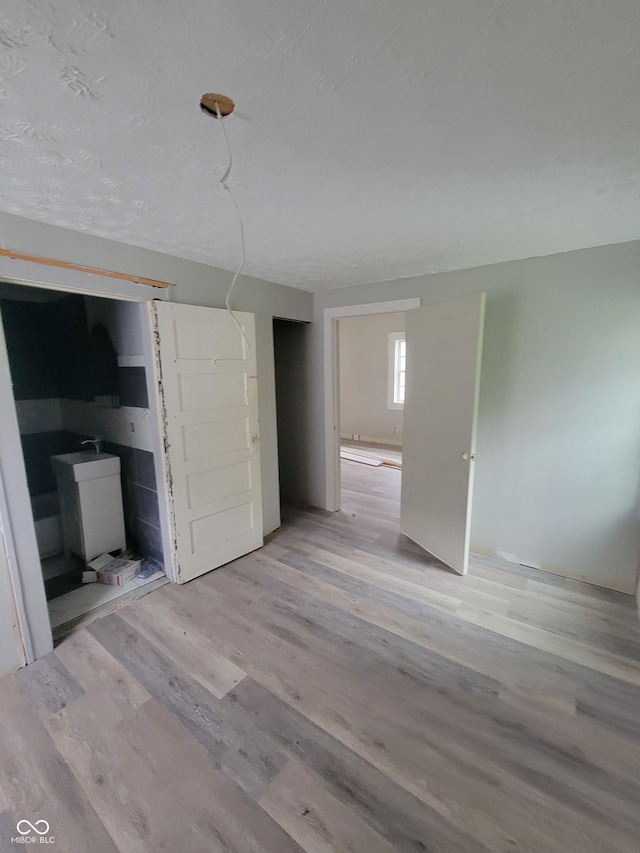 unfurnished bedroom with connected bathroom and light hardwood / wood-style flooring