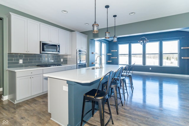 kitchen with a kitchen island with sink, sink, tasteful backsplash, white cabinetry, and stainless steel appliances