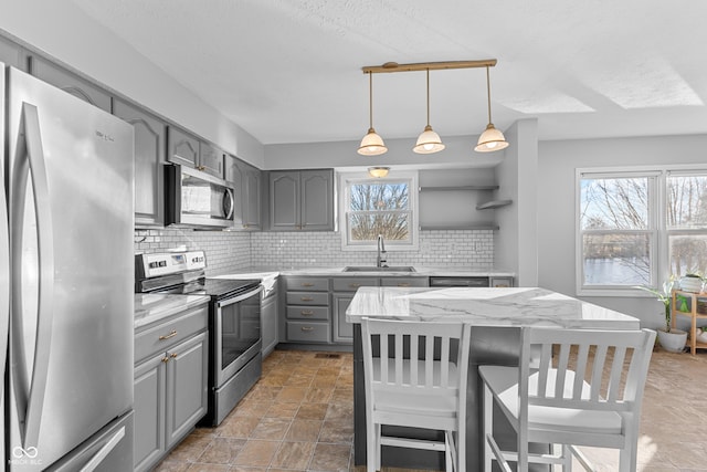 kitchen with decorative backsplash, gray cabinets, sink, and stainless steel appliances