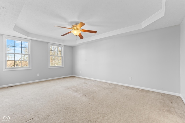 carpeted empty room featuring a tray ceiling, ceiling fan, and ornamental molding