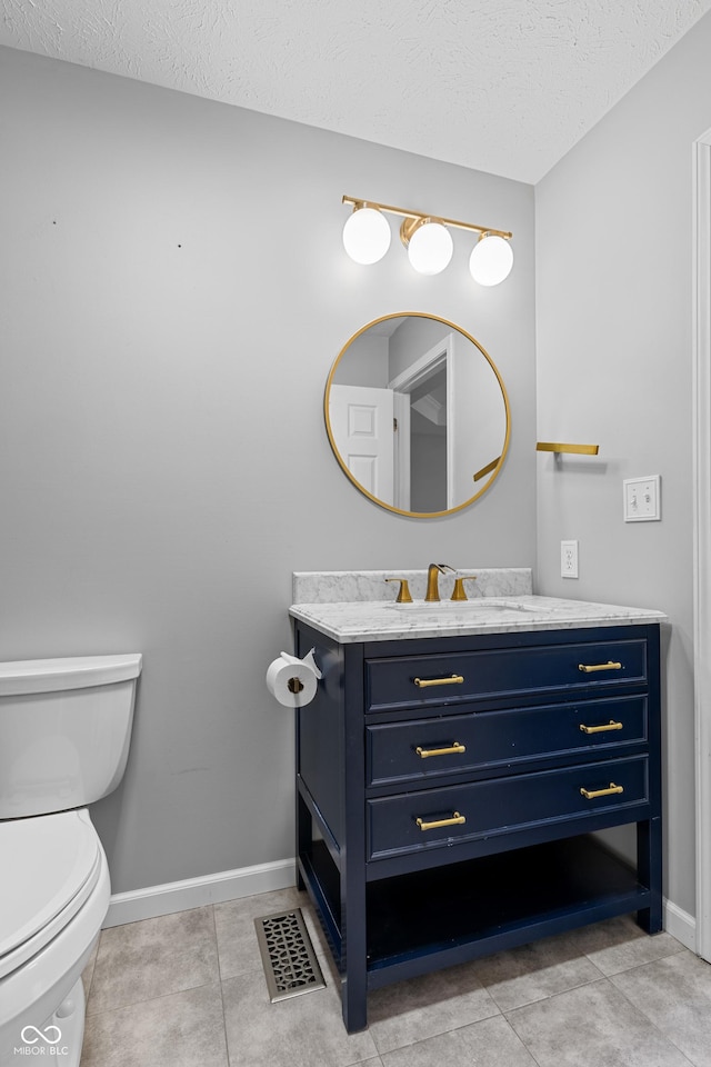 bathroom featuring tile patterned flooring, vanity, toilet, and a textured ceiling