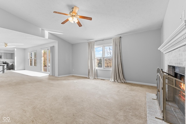 unfurnished living room featuring light carpet, a fireplace, ceiling fan, and lofted ceiling